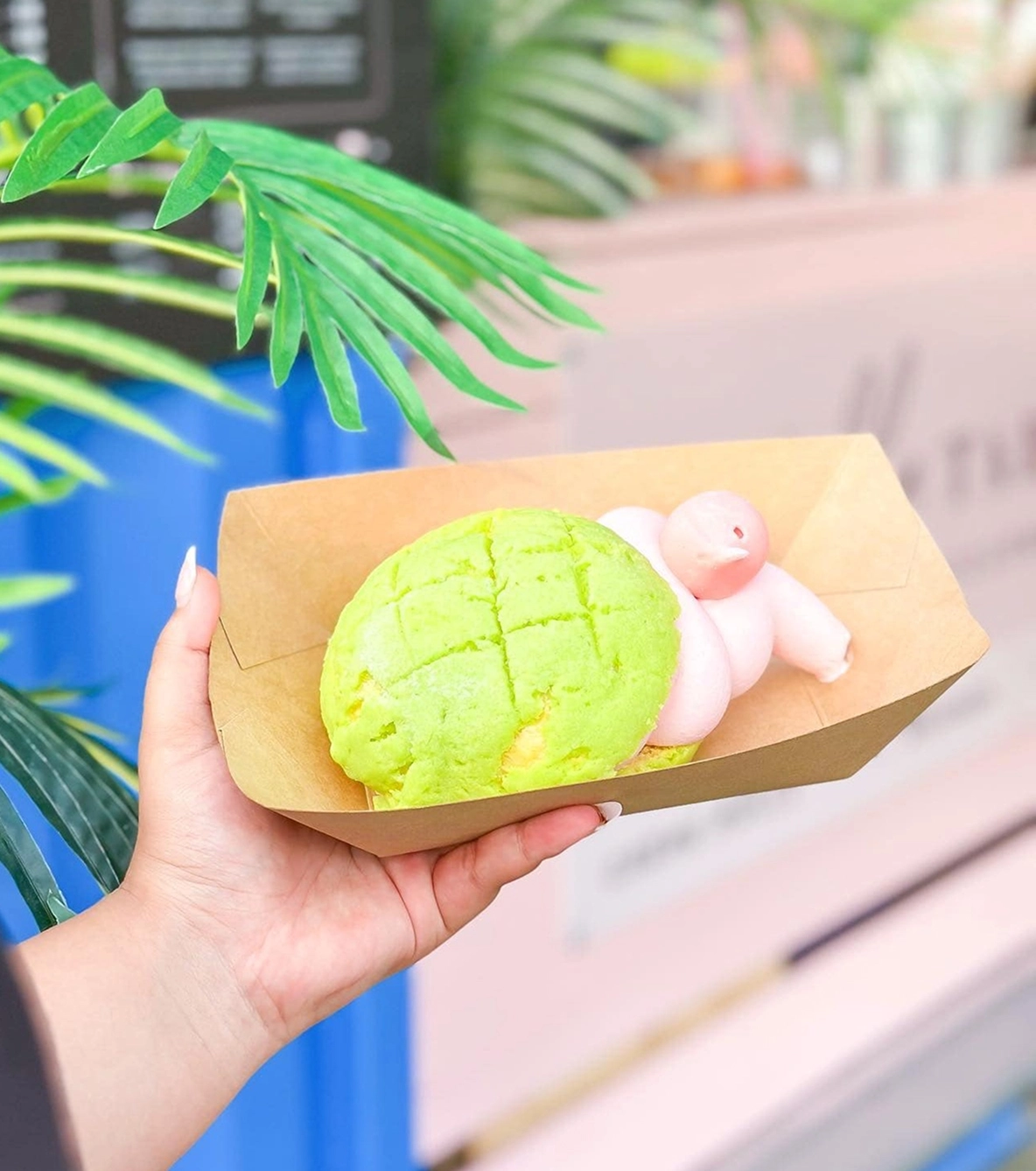 Hand holding a green melon pan with pink ice cream